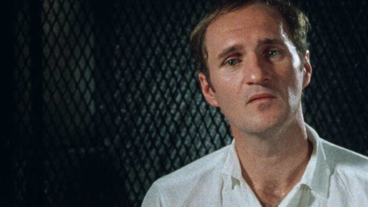 a man with a white shirts speaking to the camera